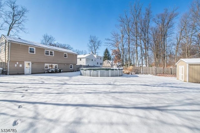 yard layered in snow featuring a shed and a covered pool