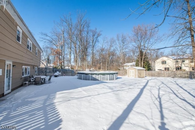 snowy yard featuring a shed and a covered pool