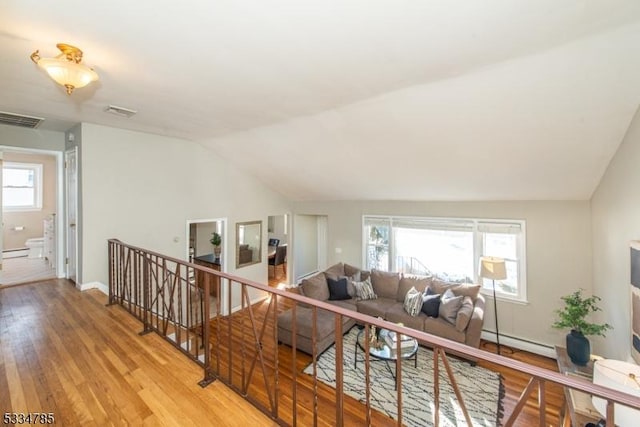 living room with lofted ceiling, a baseboard heating unit, and light hardwood / wood-style flooring