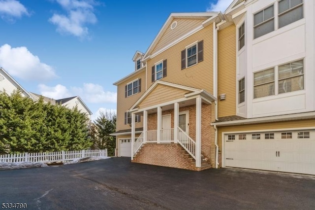 view of front of home with a garage, aphalt driveway, and fence