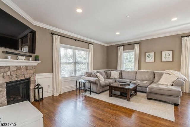 living area featuring a wainscoted wall, crown molding, a fireplace, and wood finished floors