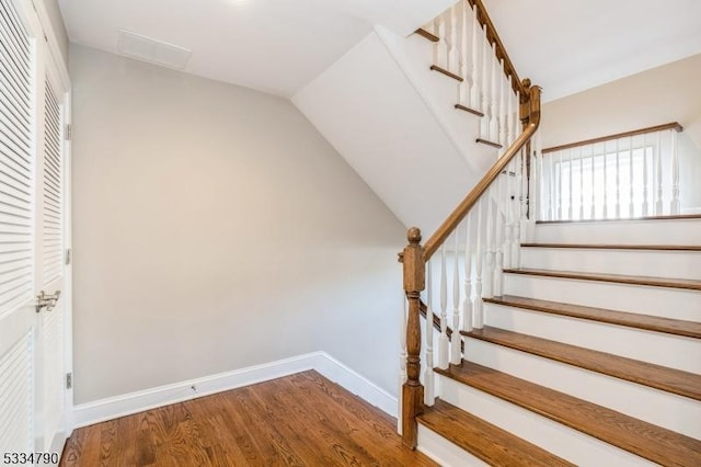 stairway with vaulted ceiling, wood finished floors, and baseboards