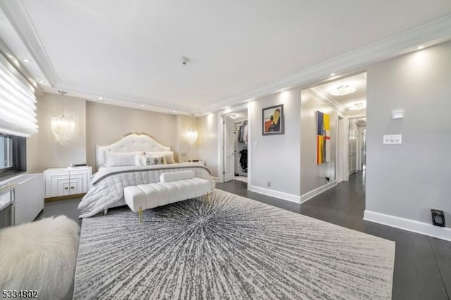 bedroom featuring dark wood-type flooring, crown molding, a walk in closet, a chandelier, and a closet