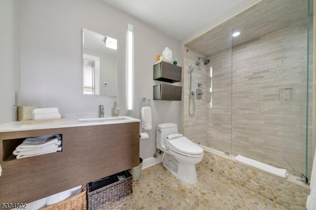 bathroom with toilet, vanity, and a shower with shower door