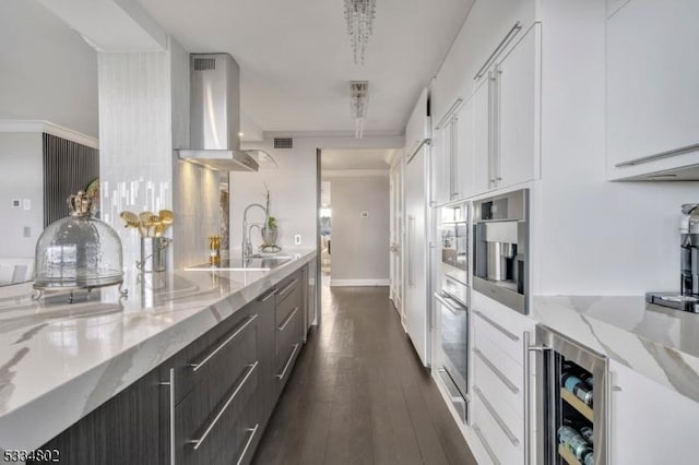 kitchen with dark hardwood / wood-style floors, wine cooler, white cabinets, light stone countertops, and wall chimney exhaust hood