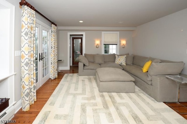 living room with a baseboard radiator, light hardwood / wood-style floors, and french doors