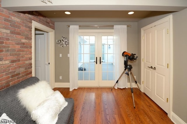 doorway to outside with french doors, brick wall, and wood-type flooring