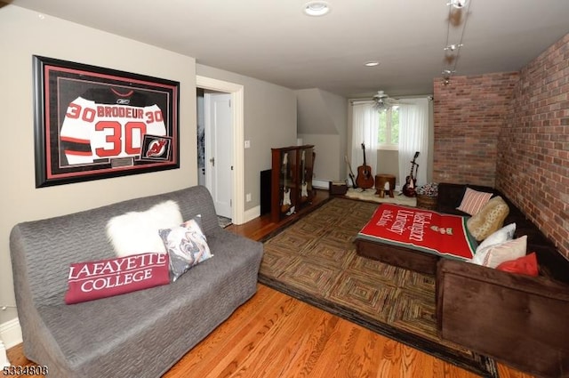 living room with hardwood / wood-style flooring and brick wall