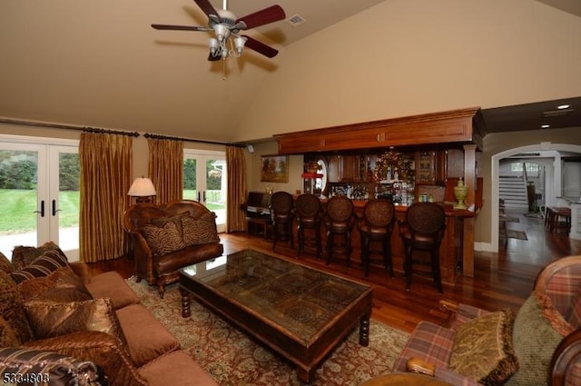 living room featuring dark wood-type flooring, high vaulted ceiling, french doors, and bar area