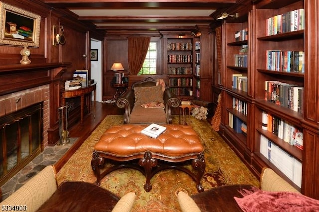 sitting room with beamed ceiling, a tile fireplace, hardwood / wood-style flooring, and wooden walls