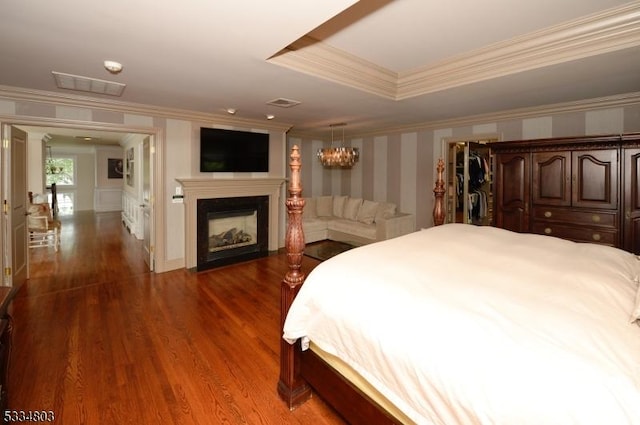 bedroom featuring a tray ceiling, crown molding, and dark wood-type flooring