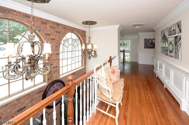 hall featuring an inviting chandelier, wood-type flooring, and brick wall