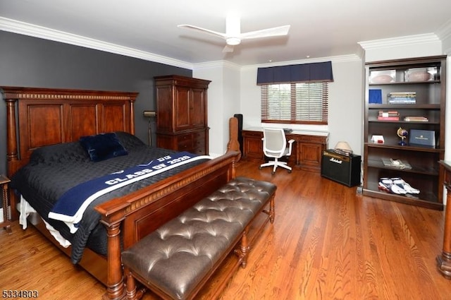 bedroom featuring wood-type flooring, built in desk, ceiling fan, and crown molding