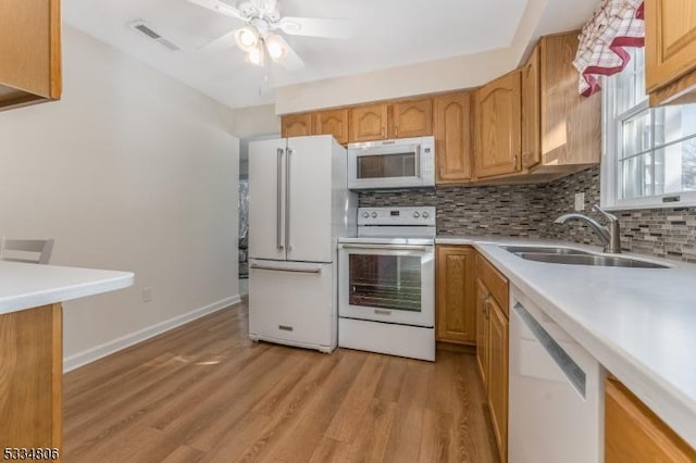 kitchen with sink, backsplash, ceiling fan, white appliances, and light hardwood / wood-style flooring