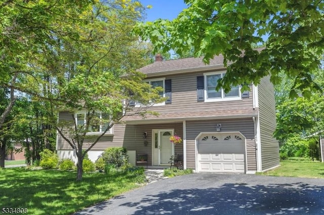 view of front of property with a garage, asphalt driveway, a chimney, and a front lawn