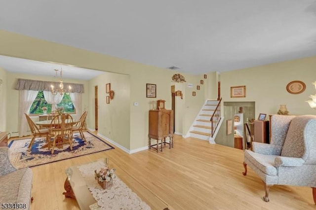 living area featuring a chandelier, wood finished floors, stairway, and baseboards