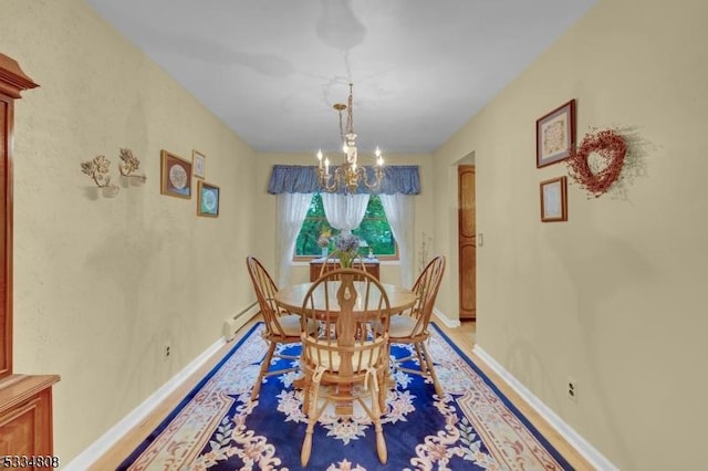 dining area featuring a chandelier, baseboards, a baseboard heating unit, and light wood-type flooring