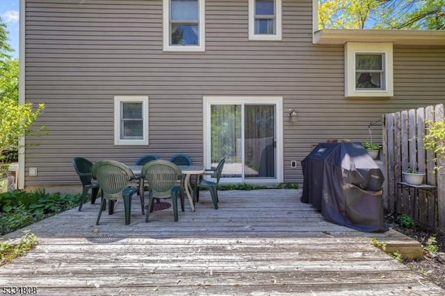 wooden deck featuring outdoor dining area, a grill, and fence