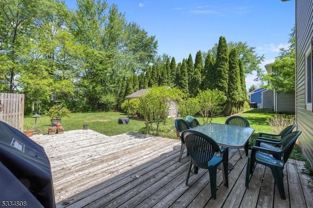 wooden terrace with outdoor dining area, a lawn, and grilling area