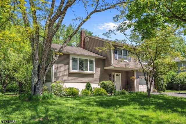 split level home with a garage, a front yard, and a chimney