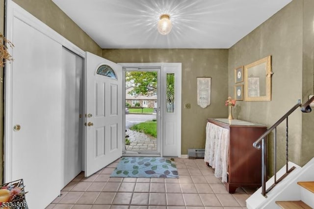 foyer with a baseboard heating unit, light tile patterned floors, and stairway