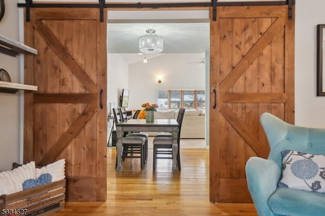 dining room featuring a barn door, lofted ceiling, and light wood-type flooring