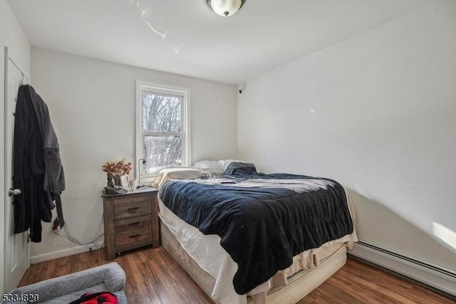 bedroom featuring a baseboard heating unit and dark hardwood / wood-style floors