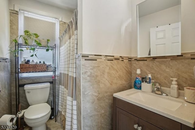 bathroom with vanity, a shower, tile walls, and toilet