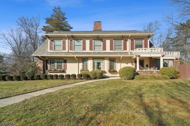 view of front facade with a chimney, a front lawn, and stucco siding