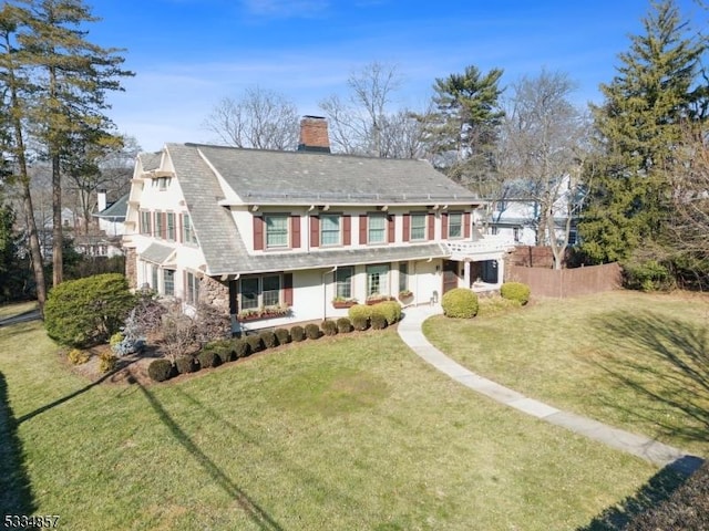 view of front facade featuring a front yard, fence, and a chimney