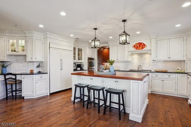 kitchen featuring stainless steel appliances, a breakfast bar, white cabinets, and wood counters