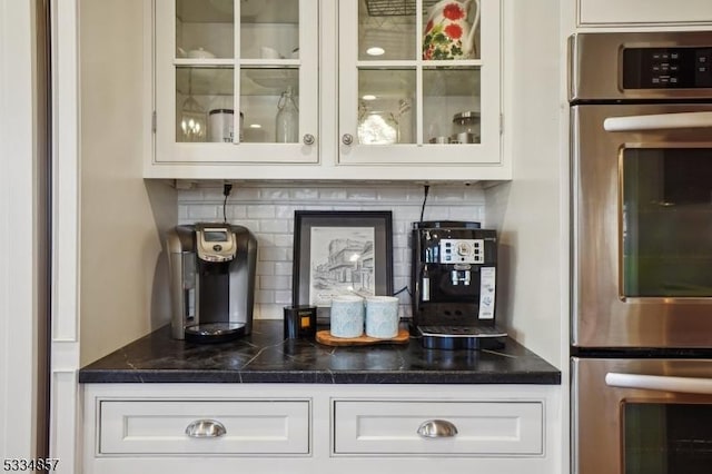 bar featuring stainless steel double oven and backsplash