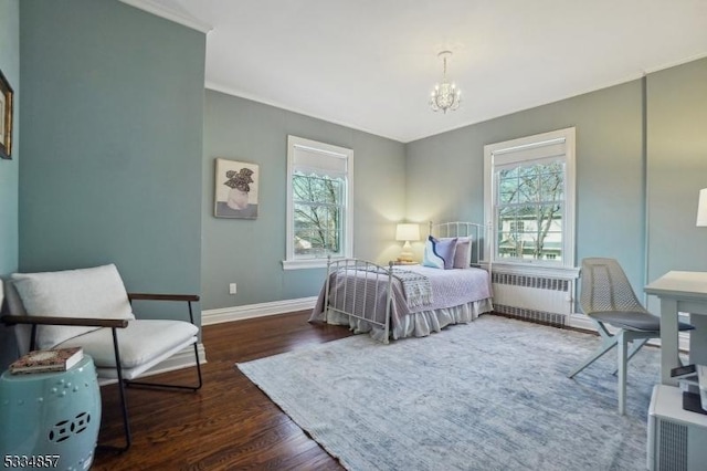 bedroom featuring an inviting chandelier, radiator heating unit, multiple windows, and wood finished floors