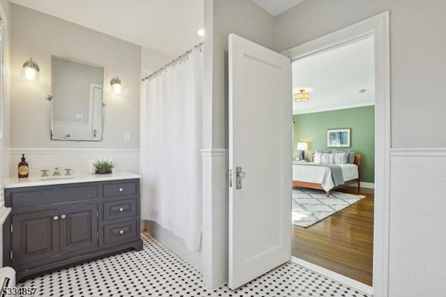 full bathroom with curtained shower, wainscoting, connected bathroom, and vanity