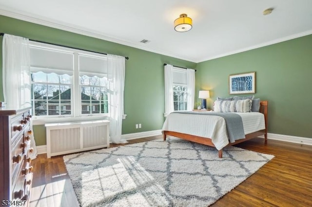 bedroom featuring radiator, multiple windows, visible vents, and wood finished floors