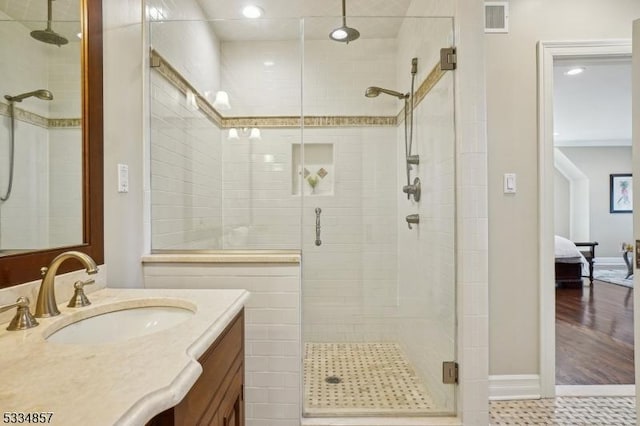 ensuite bathroom with baseboards, visible vents, connected bathroom, vanity, and a shower stall