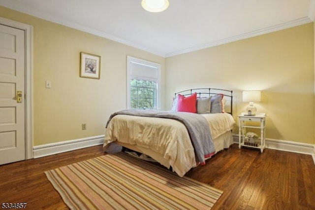 bedroom featuring baseboards, wood finished floors, and crown molding