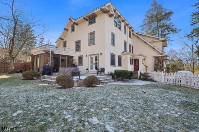 back of property with french doors, fence, a sunroom, and stucco siding