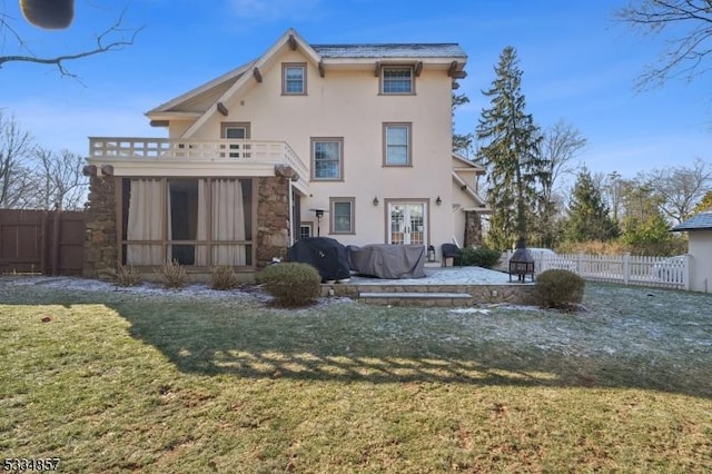 back of property with stucco siding, a lawn, a patio area, fence, and a balcony