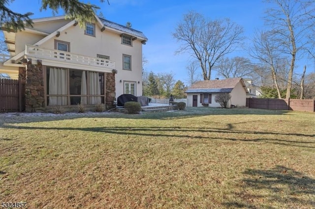 back of property with a balcony, fence, and a lawn