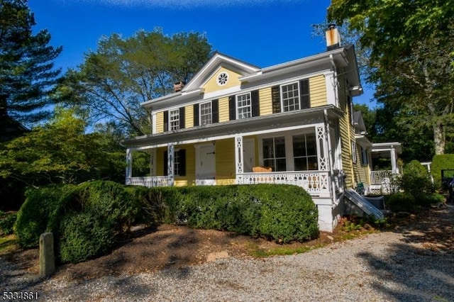 view of front of home with a chimney and a porch