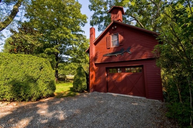 exterior space featuring a garage, driveway, and an outdoor structure