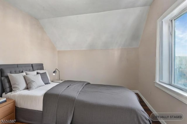 bedroom featuring lofted ceiling, hardwood / wood-style floors, and multiple windows