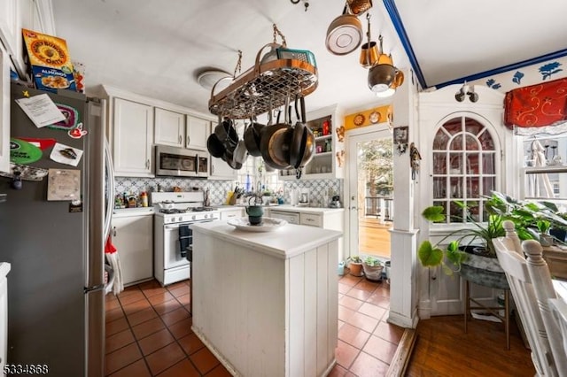 kitchen featuring white cabinetry, tasteful backsplash, a kitchen island, dark tile patterned floors, and stainless steel appliances