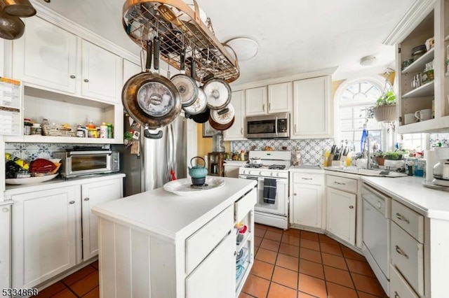 kitchen with light tile patterned floors, white appliances, a center island, tasteful backsplash, and white cabinets