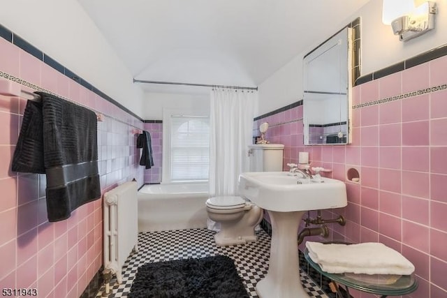 bathroom with lofted ceiling, radiator, tile walls, a tub, and toilet