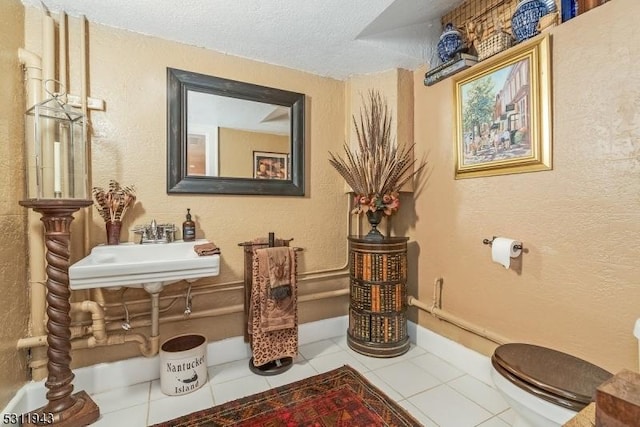 living area featuring sink, tile patterned flooring, and a textured ceiling