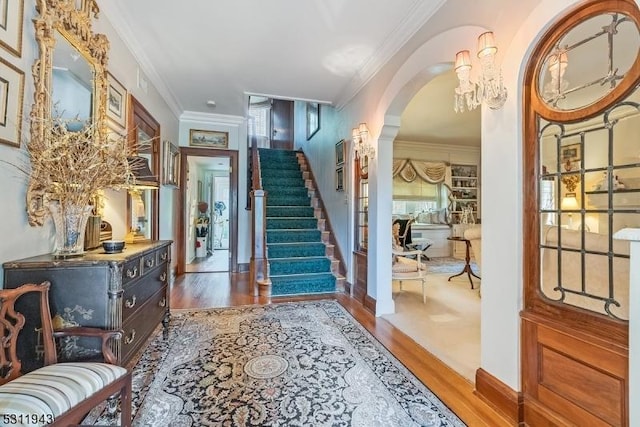 foyer entrance featuring hardwood / wood-style floors, ornamental molding, and a chandelier