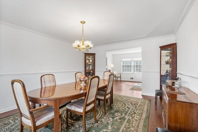 dining area featuring a notable chandelier, baseboards, wood finished floors, and crown molding