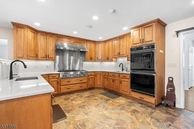 kitchen featuring stainless steel gas stovetop, dobule oven black, a sink, and under cabinet range hood